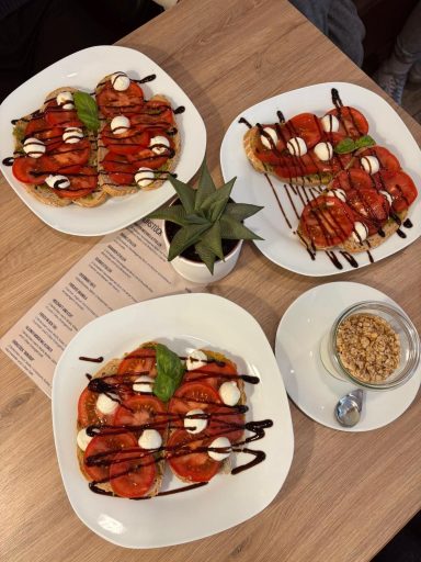 Foto von einem Tisch mit Tomaten-Mozzarella-Stullen auf  3 Tellern angerichtet