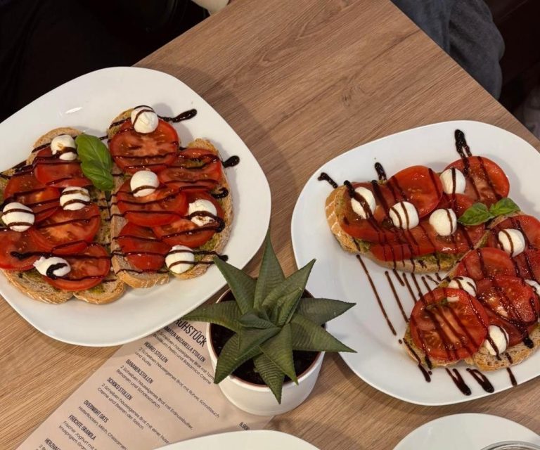 Tomaten-Mozzarella-Stullen Frühstücksangebot: Tomaten-Mozzarella-Stullen, garniert mit Balsamico-Creme und einem Blatt Basilikum