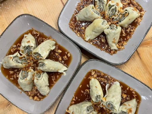 hausgemachte Fleischmaultaschen, halbiert in Bratensoße und angerichtet mit Röstzwiebeln