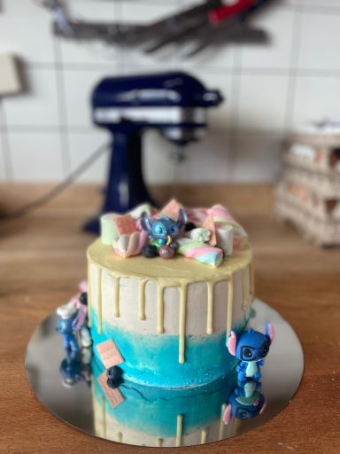 Weiß-blaue Torte zum Thema "Stitch" mit rosa Schokoladentafeln, Marshmallows und Stitch-Figuren 