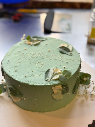 Grüne Torte mit Namen und Alter des Geburtstagskindes. Dekoriert mit Buttercreme-Art, Schleierkraut und Perlern in verschiedenen Größen.  